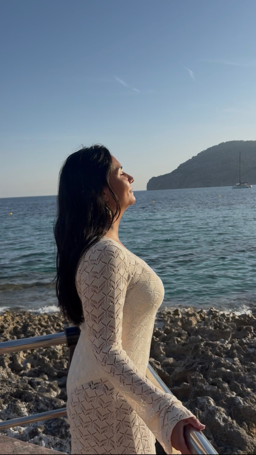 Jacqueline med ansiktet vänt mot solen vid havet
